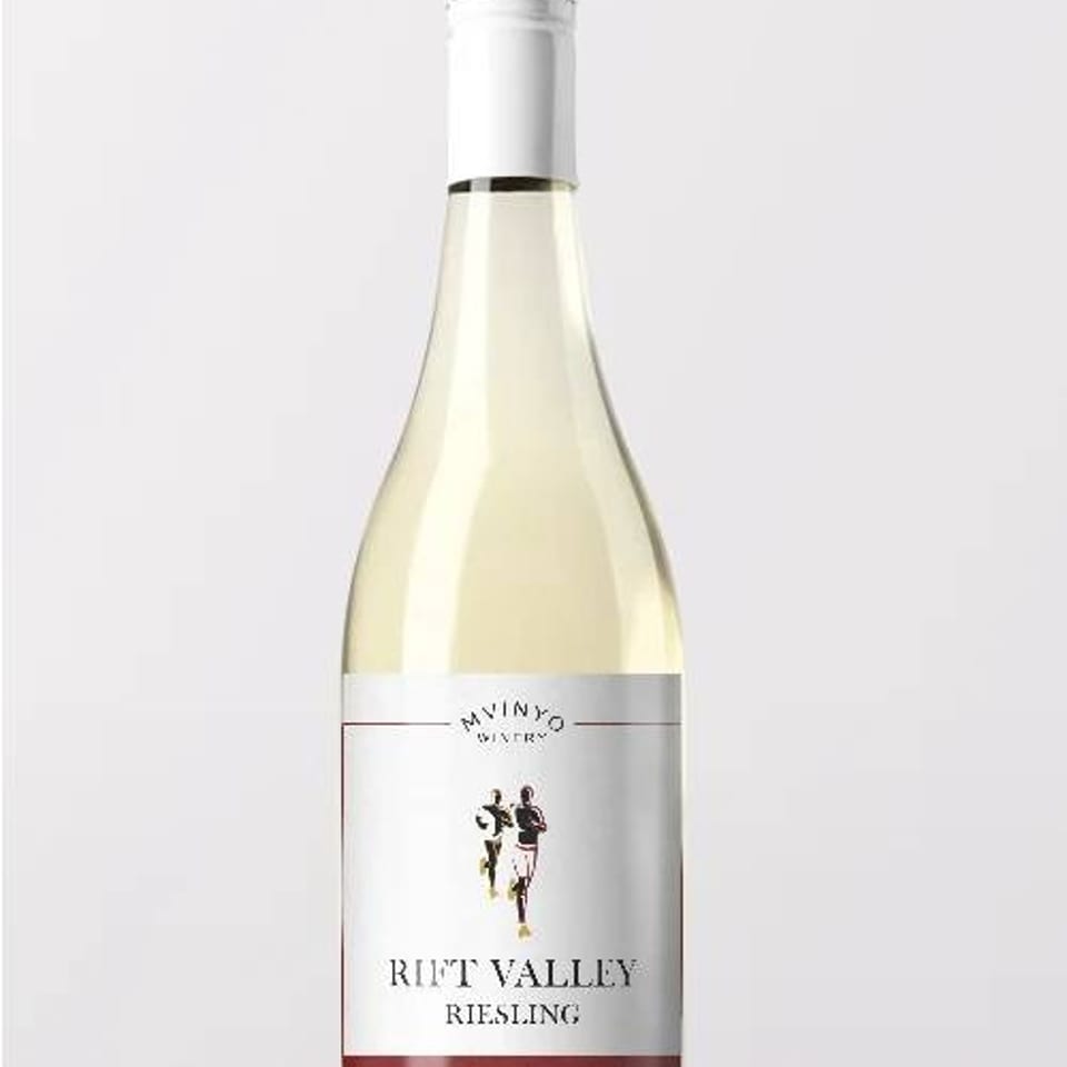 Bottle of Rift Valley Riesling white wine standing on a white wooden surface against a plain background.